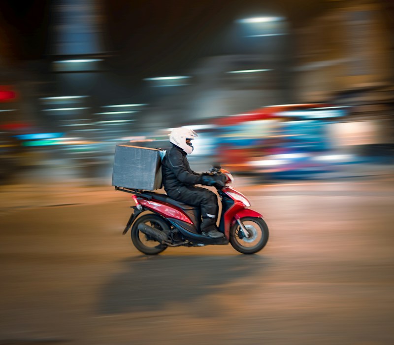 Delivery rider on a scooter at night